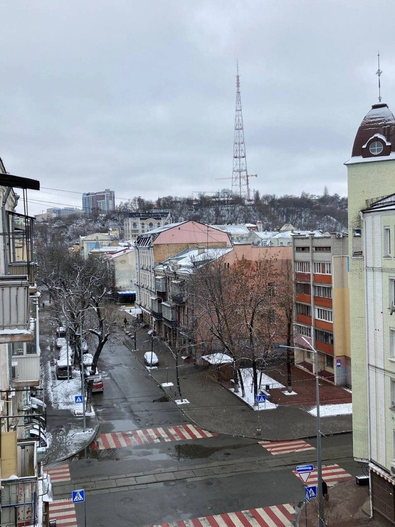 A street surrounded by houses and leafless trees. There is snow in places.