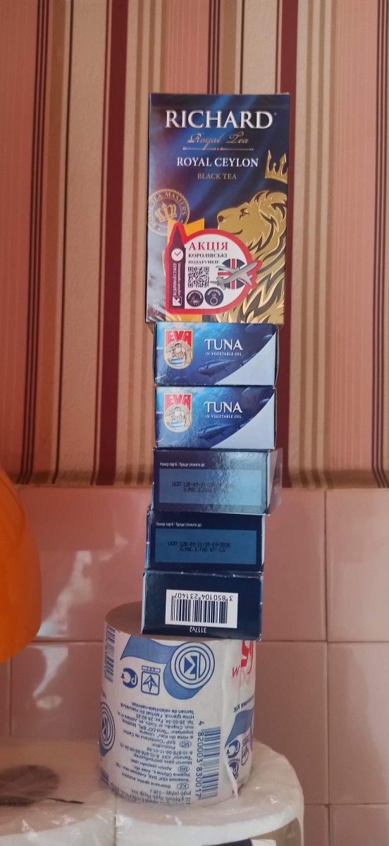 Several tins and packets of food stacked on top of each other.
