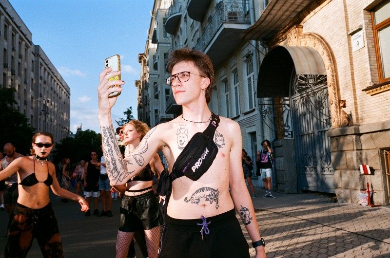 Ein Mann mit vielen Tattoos auf einer Straße mit anderen Personen.