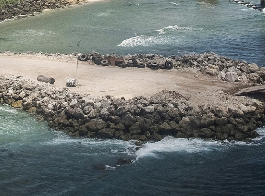 A land train with many stones by a body of water.