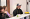 People and groups of people sitting and standing at tables. They smile, speak or present things, which are not visible to the viewer