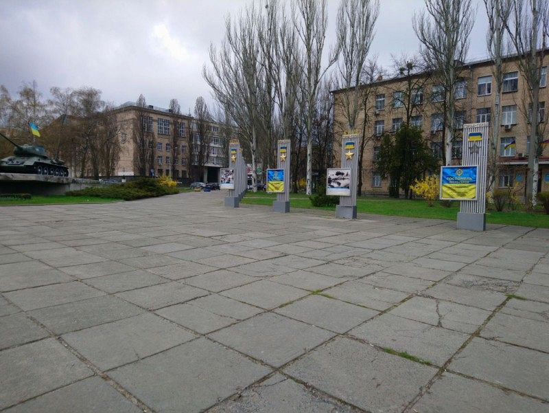 A square with a paved floor on which there are several display boards with yellow and blue motifs
