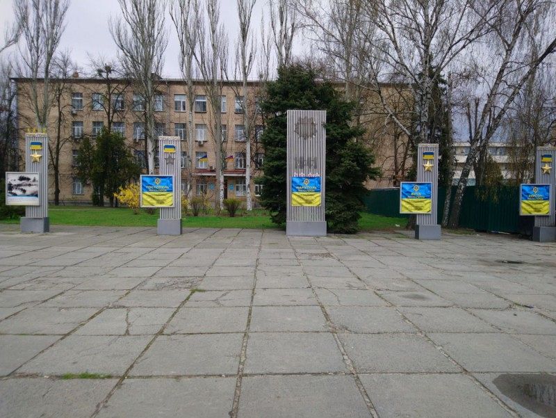 A square with a paved floor on which there are several display boards with yellow and blue motifs.