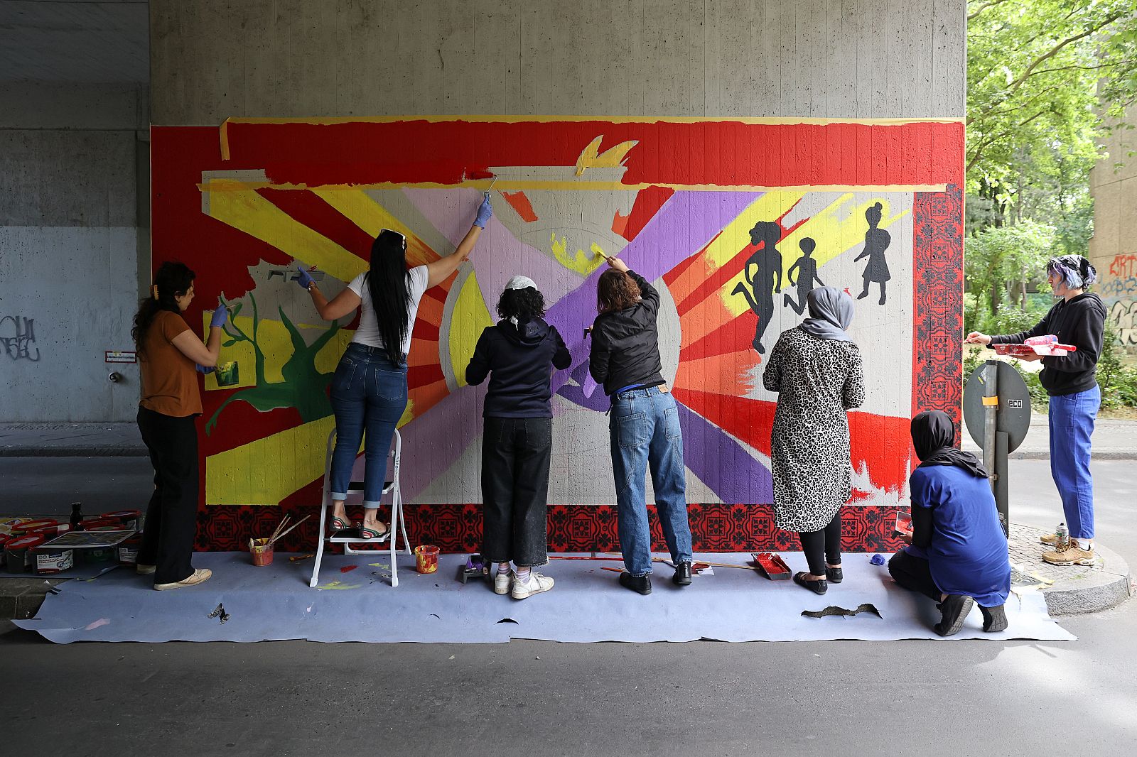 Several people paint a picture on a wall