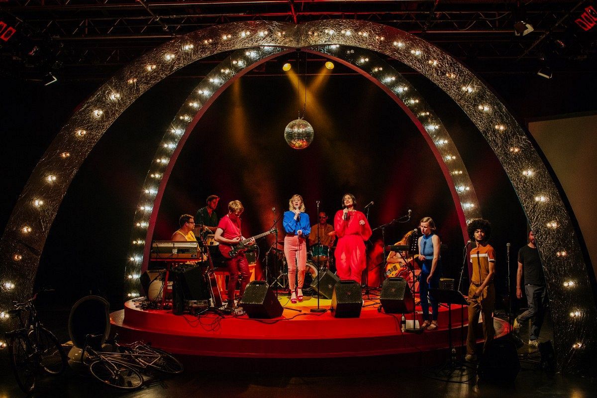 A band stands on a colorfully lit stage.